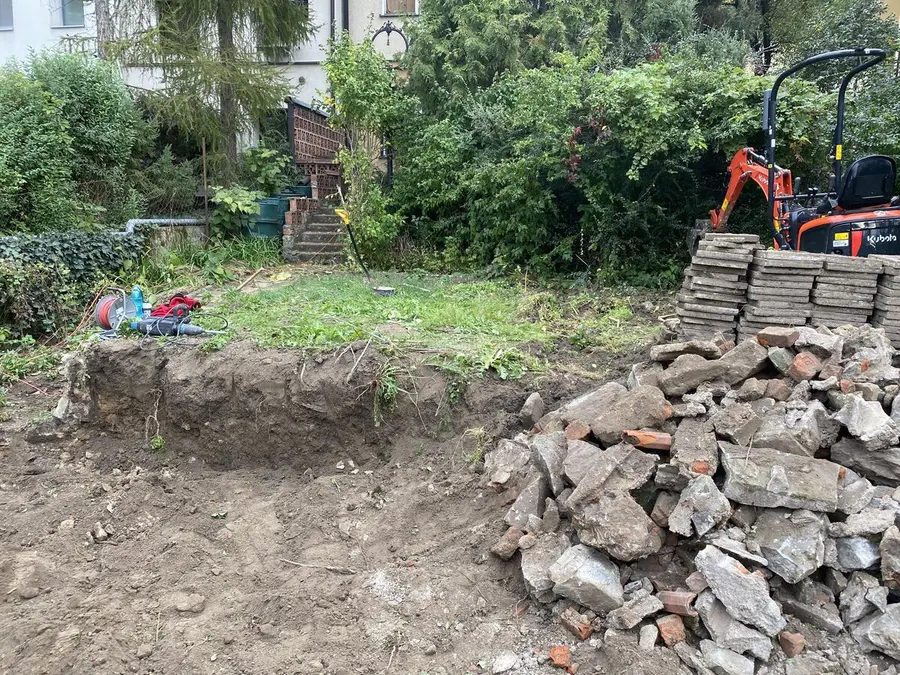 Bagr nad rozebranou zdí, hromada kamene, Brno
