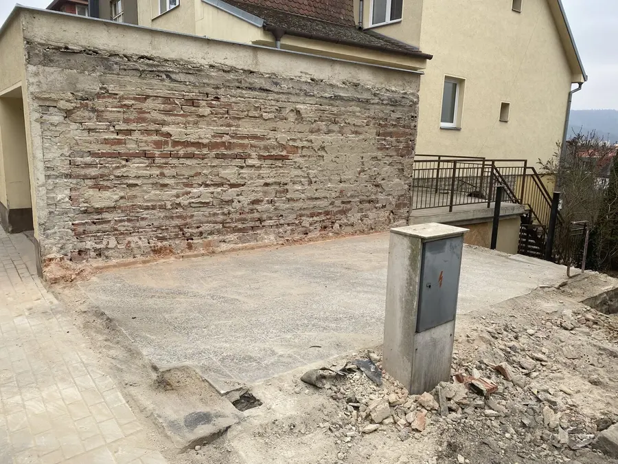 Hotová betonová plocha a odkrytá cihlová zeď, Brno