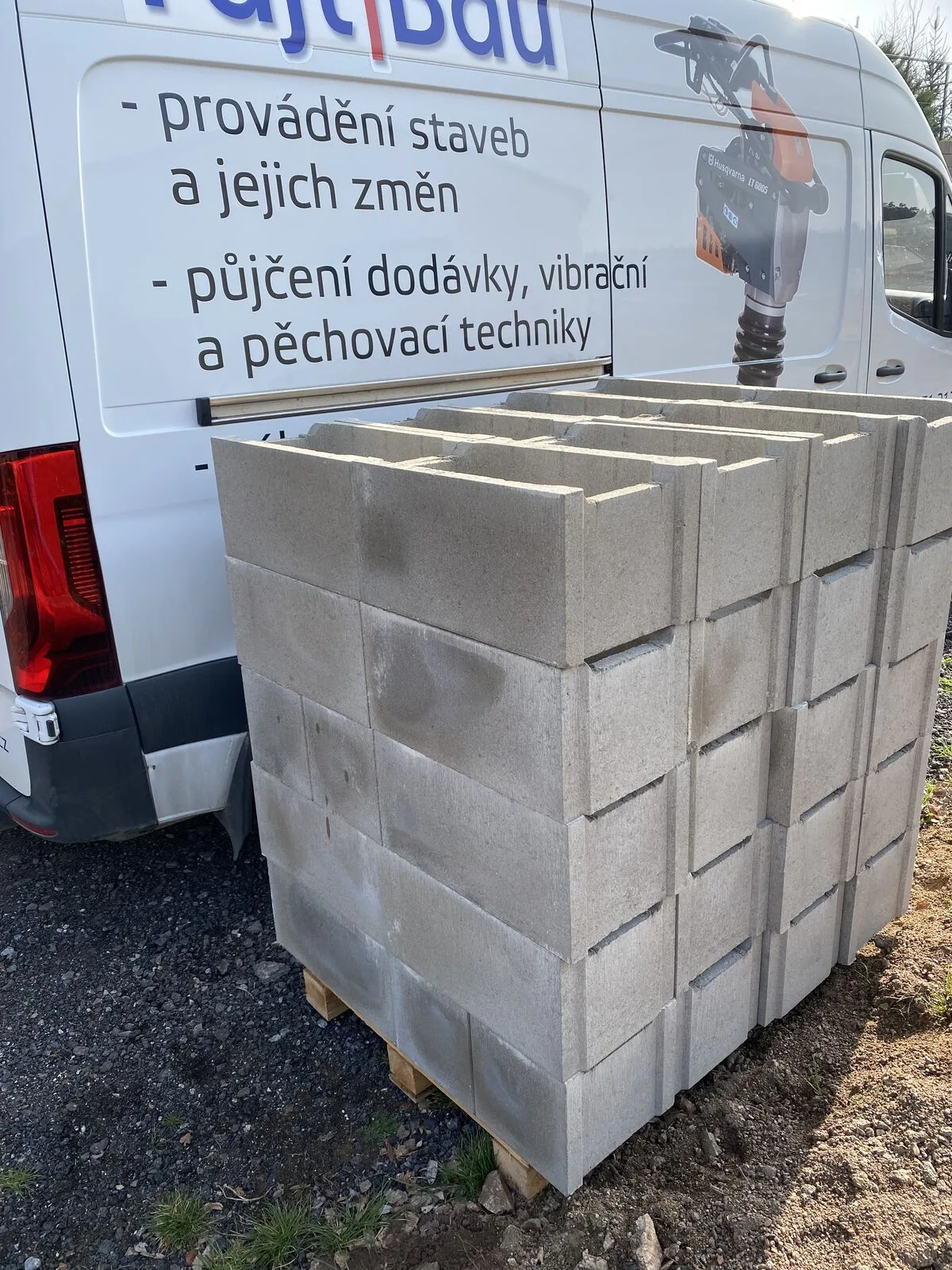 Otevřené zadní dveře dodávky FAJTBAU s nabídkou služeb, naložené palety
